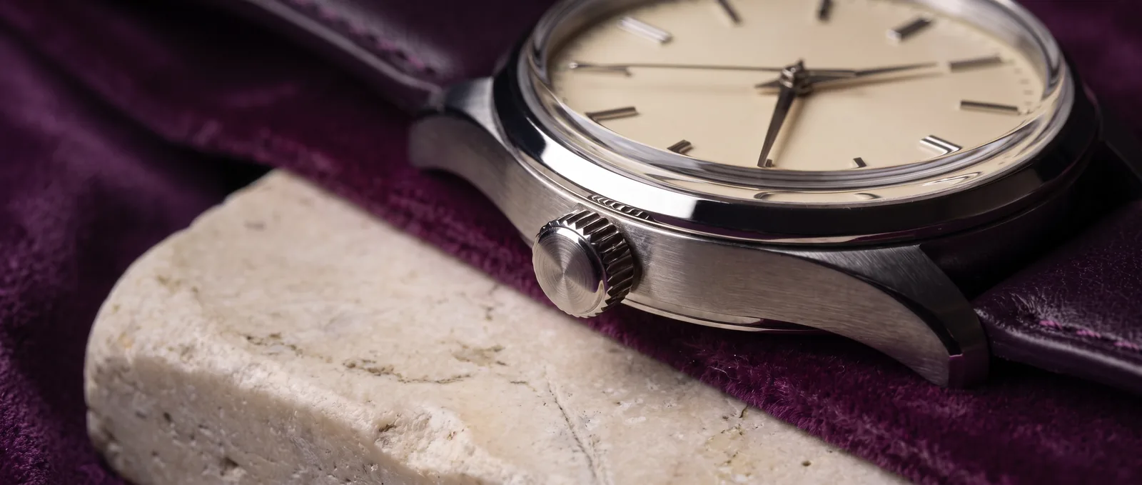 Editorial detail of a watch dial, brushed case and winding crown